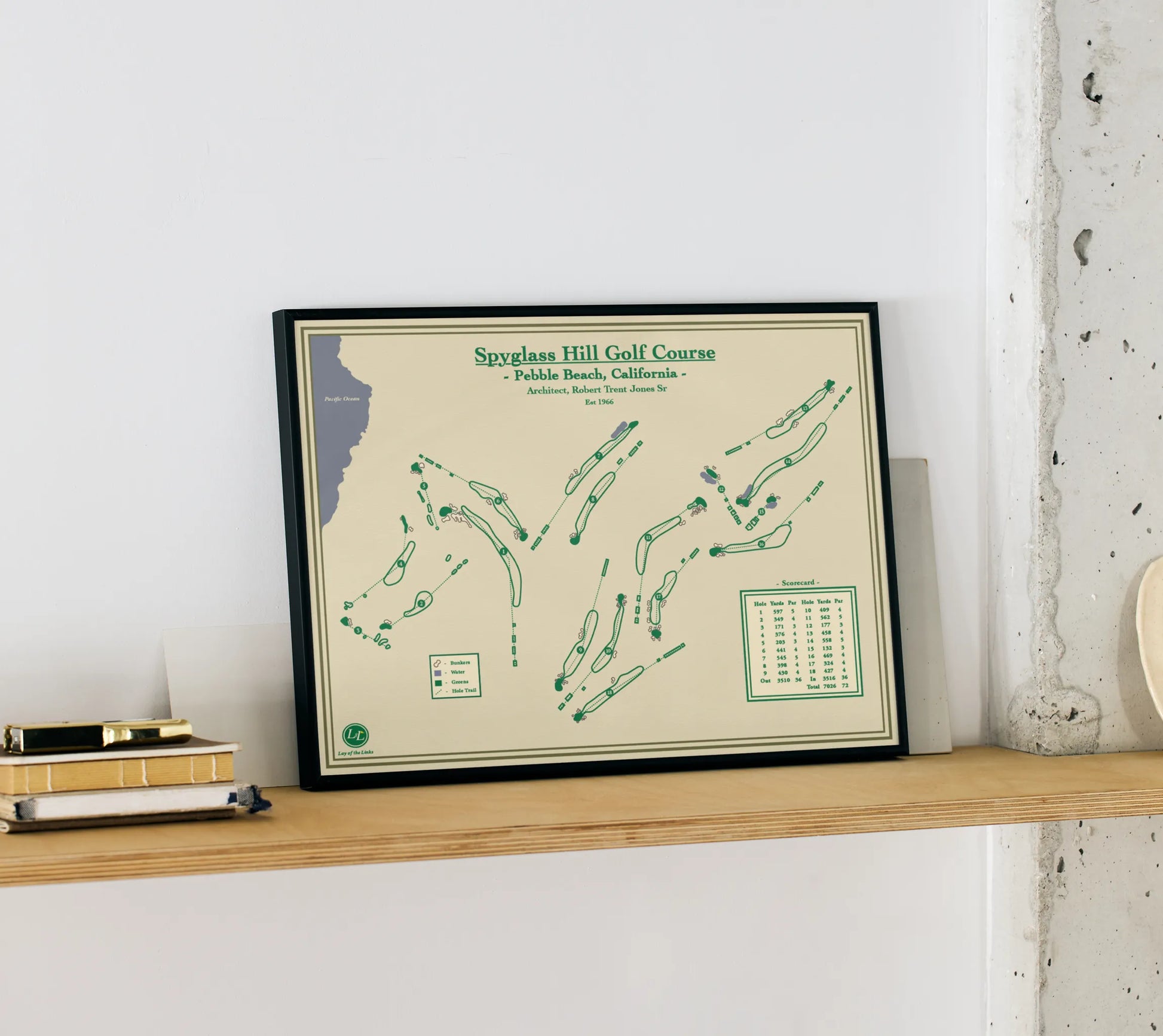 Framed golf course map onf spyglass hill golf course on a shelf against a white wall