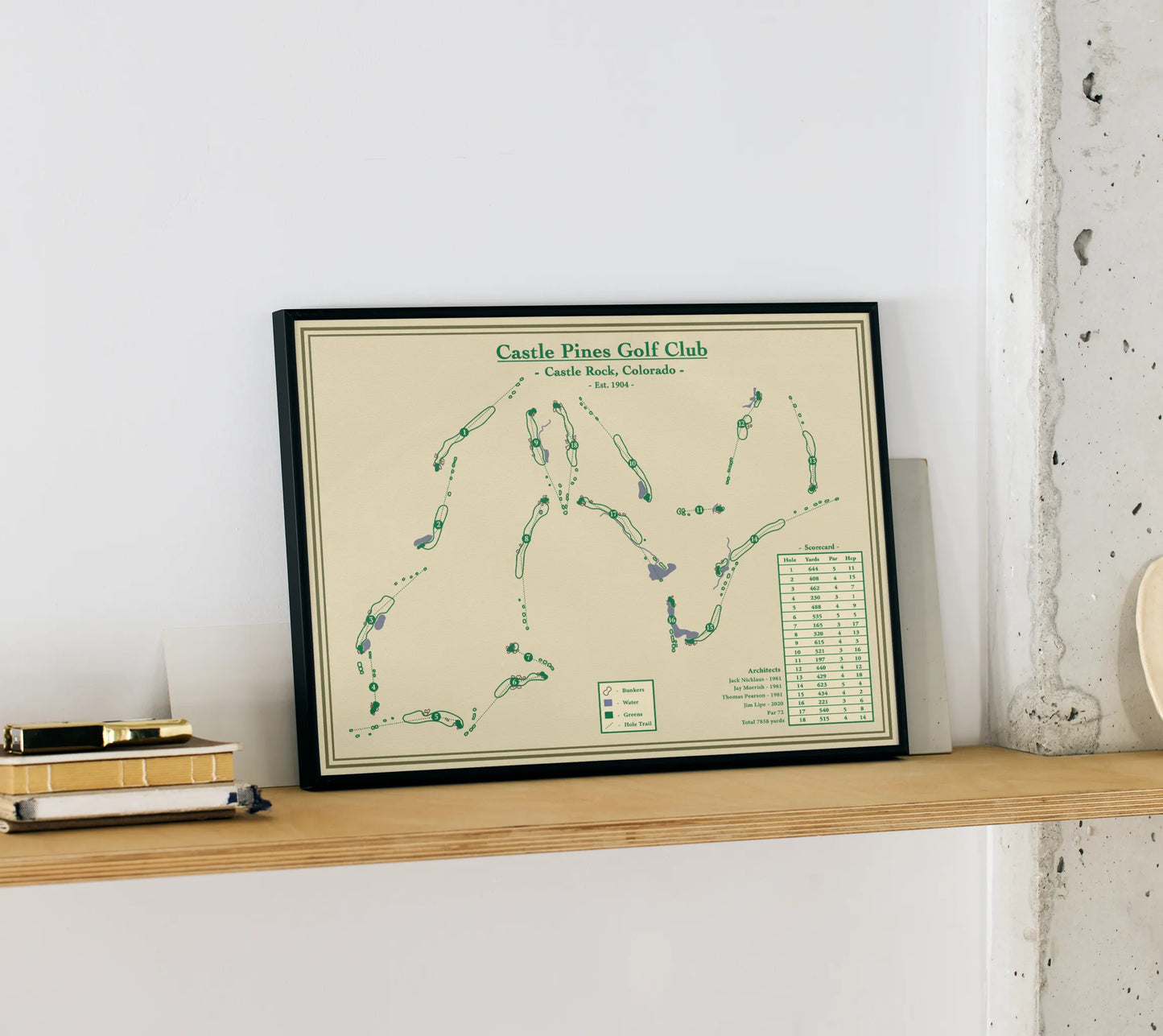Blueprint map art of Castle Pines Golf Club on a wooden shelf against a white wall.