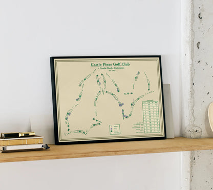 Blueprint map art of Castle Pines Golf Club on a wooden shelf against a white wall.