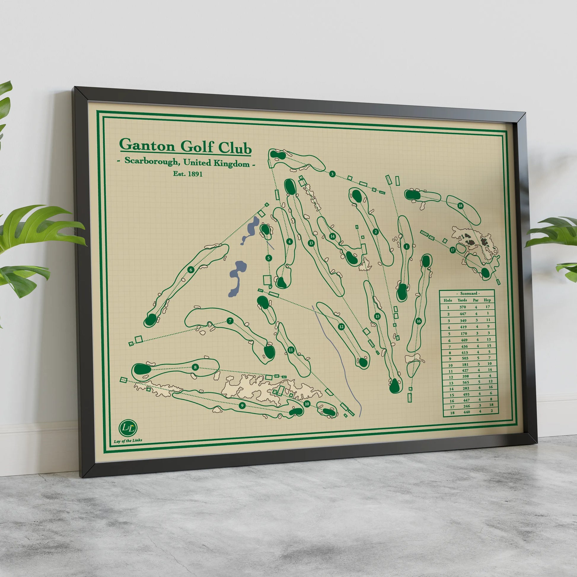 A framed golf course map print for Ganton Golf Club, Scarborough, United Kingdom, featuring a cream background with green course markings and a black frame, styled on a marble surface against a white wall with green leaves at the sides.