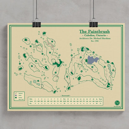 A vintage-style golf course map poster titled 'The Paintbrush' hanging against a light gray wall with black binder clips.