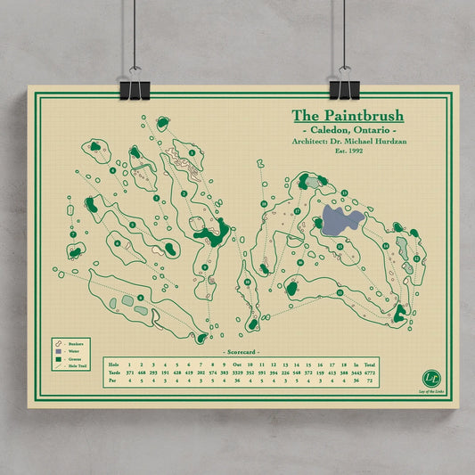 A vintage-style golf course map poster titled 'The Paintbrush' hanging against a light gray wall with black binder clips.