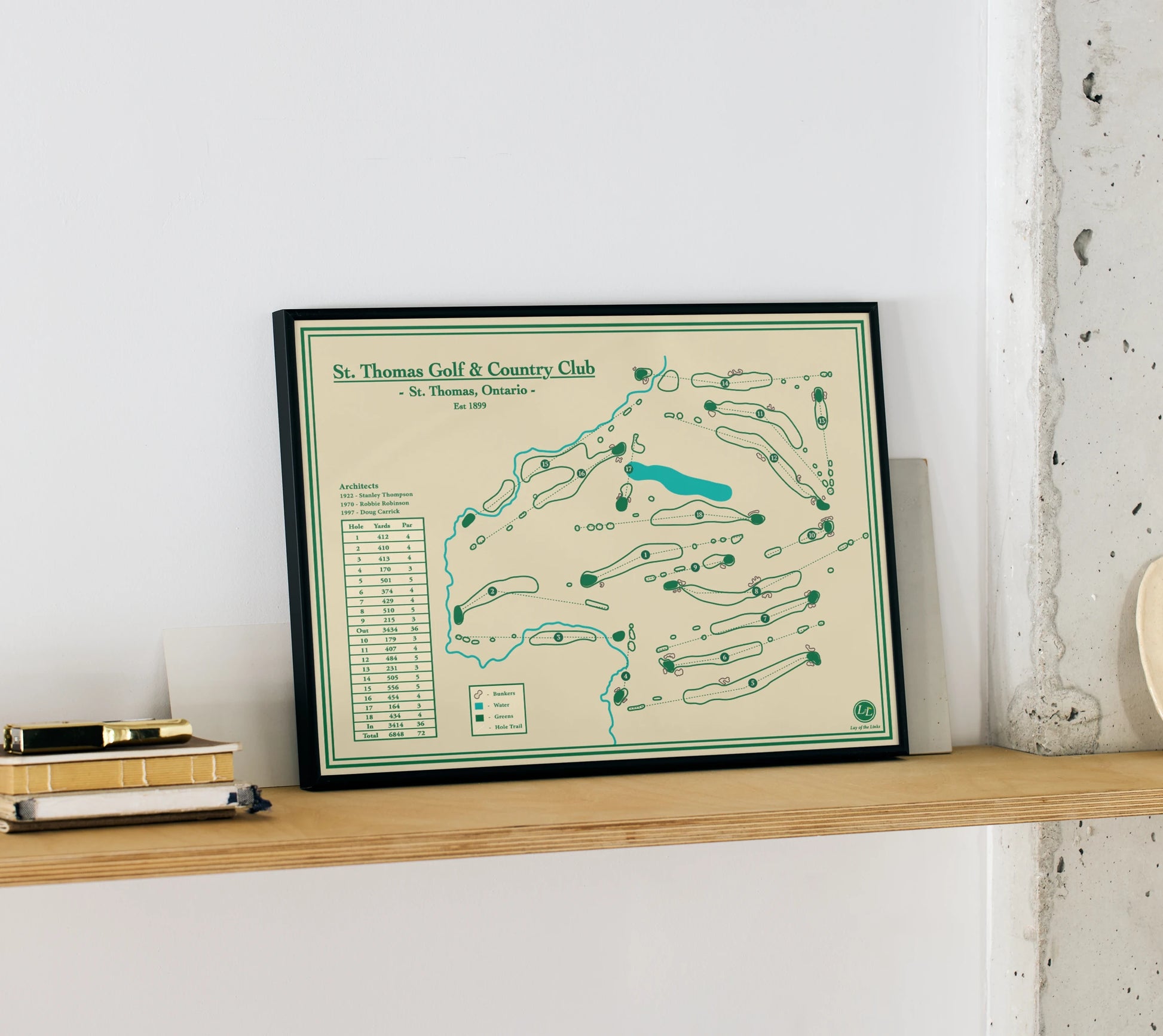 Framed map of St. Thomas Golf & Country Club on a shelf against a white wall.