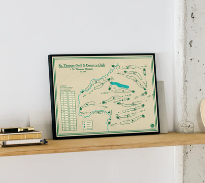 Framed map of St. Thomas Golf & Country Club on a shelf against a white wall.