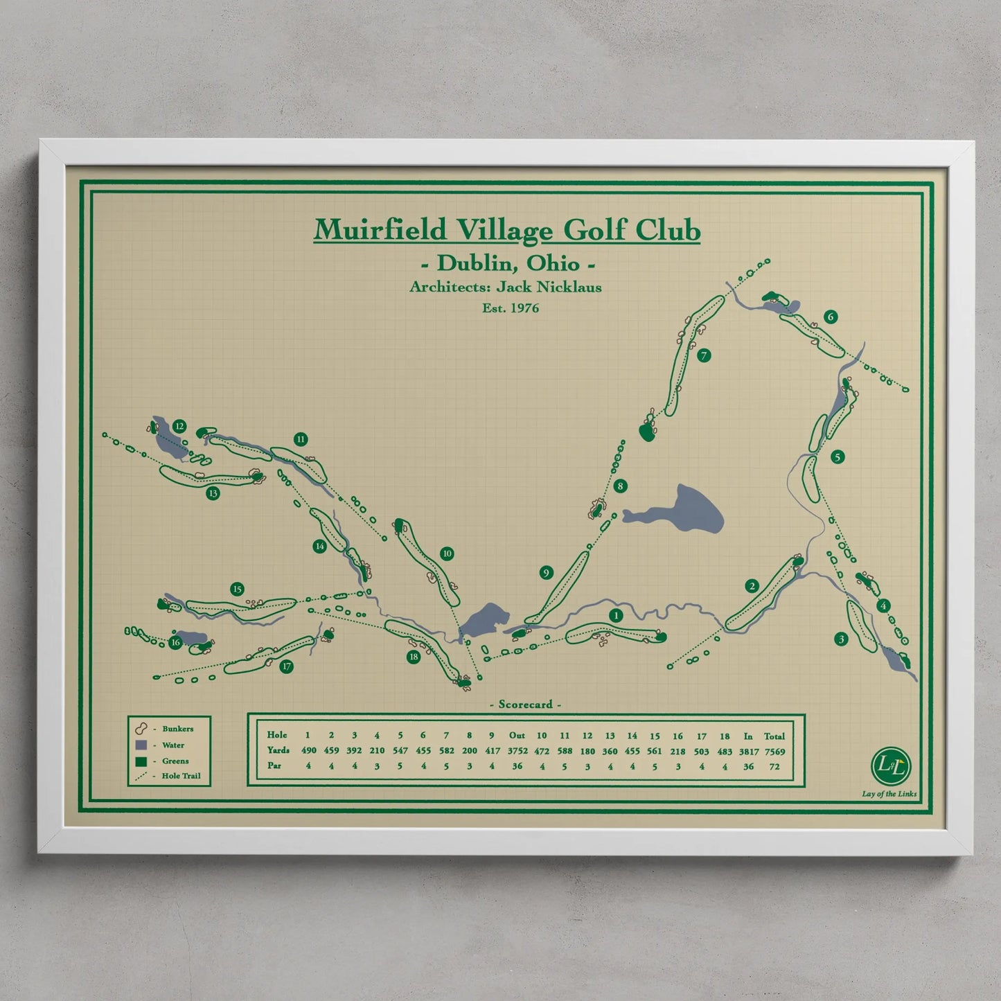 Muirfield Village Golf Club map print hanging on a light gray wall. The print features a golf course layout with green paths, blue water features, and a beige background with green and black text.