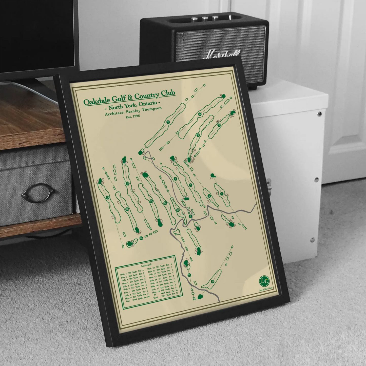 Framed golf course map on a carpeted floor with a speaker in the background