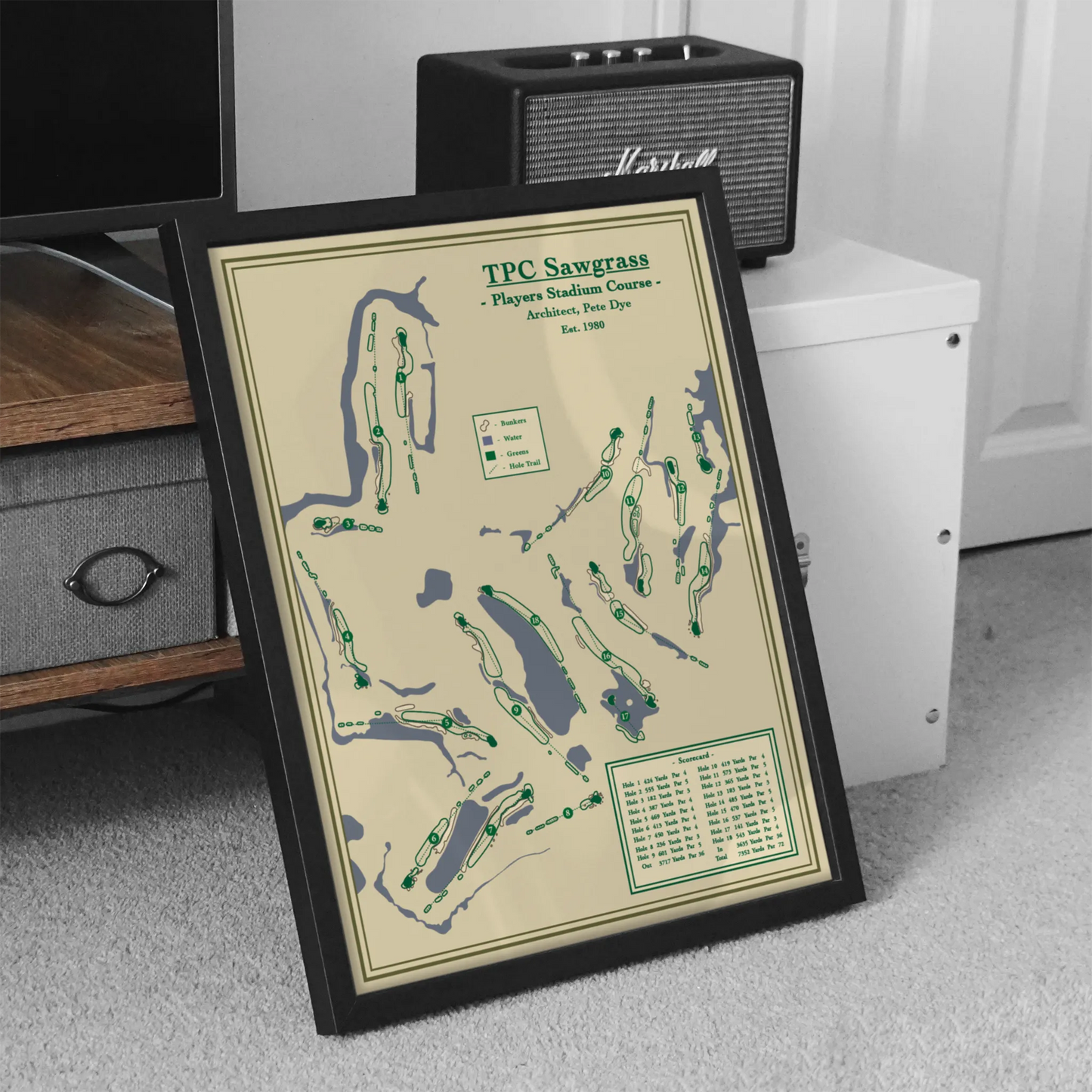 Framed golf course map of TPC Sawgrass on a carpeted floor with a Marshall speaker in the background.