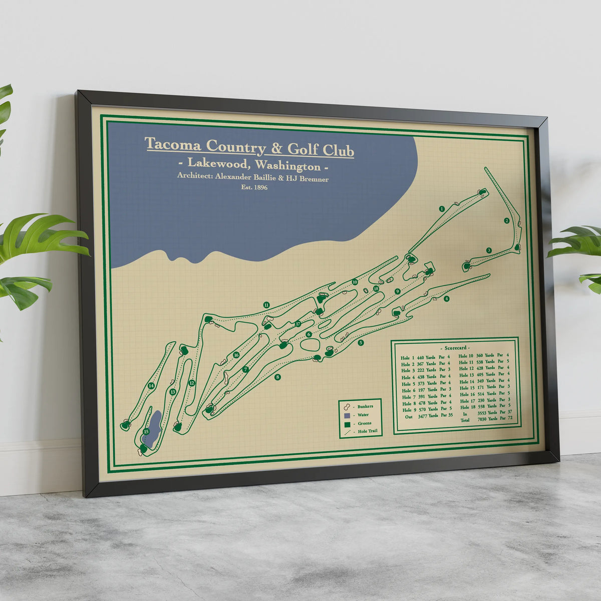 A framed golf course map print of Tacoma Country & Golf Club leaning against a white wall on a light marble surface, with green leaves visible at the sides.