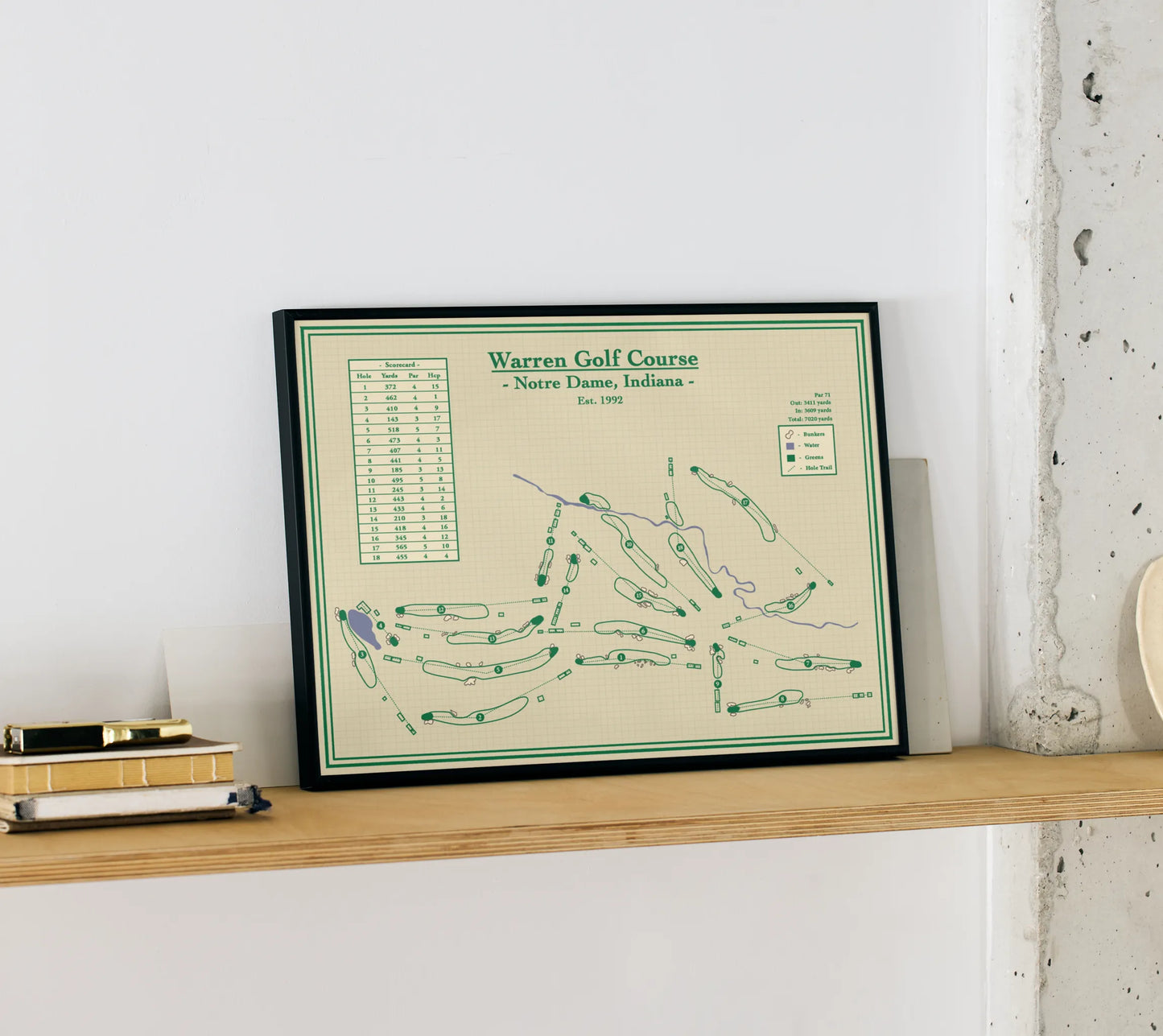 Framed course map of Warren Golf Course on a wooden shelf against a white wall.