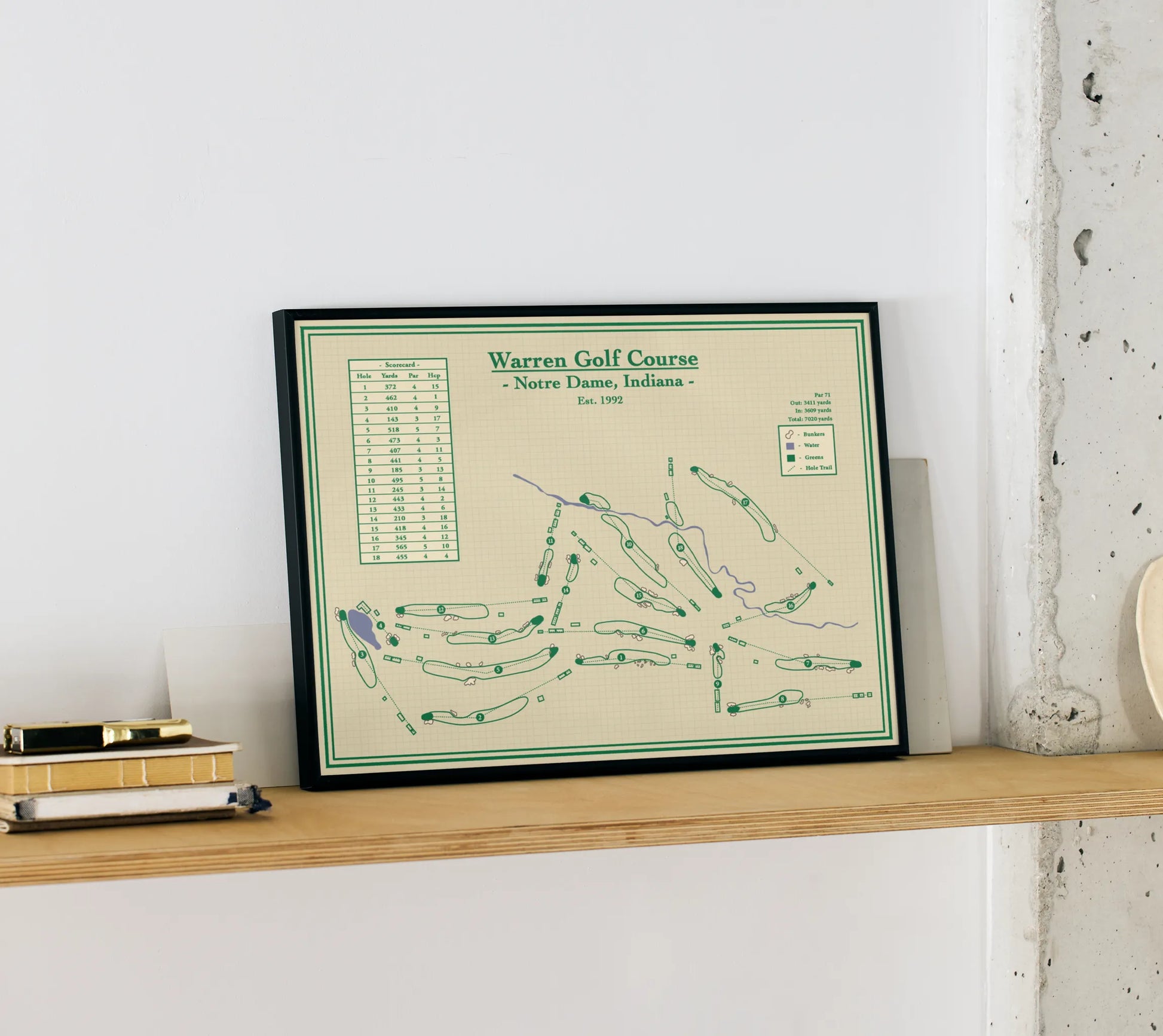 Framed course map of Warren Golf Course on a wooden shelf against a white wall.